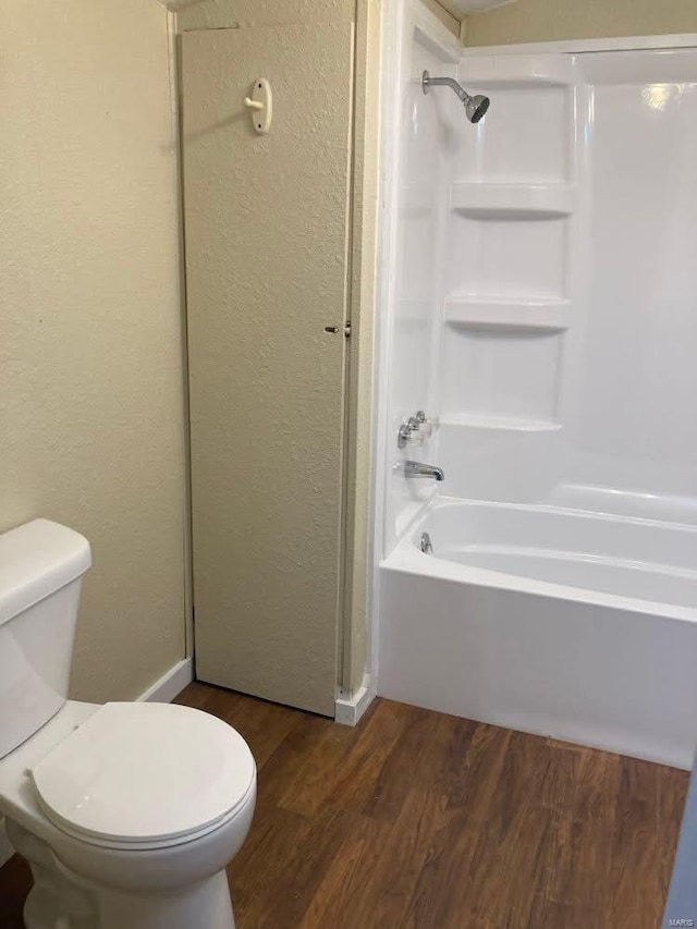 bathroom with hardwood / wood-style floors, shower / bathtub combination, and toilet