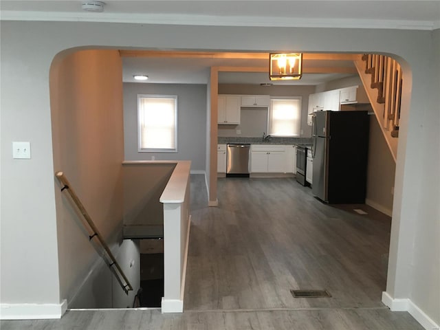 kitchen featuring wood-type flooring, white cabinetry, ornamental molding, and appliances with stainless steel finishes