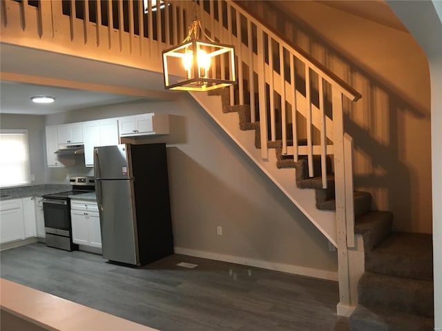 kitchen with pendant lighting, white cabinets, dark hardwood / wood-style floors, light stone counters, and stainless steel appliances