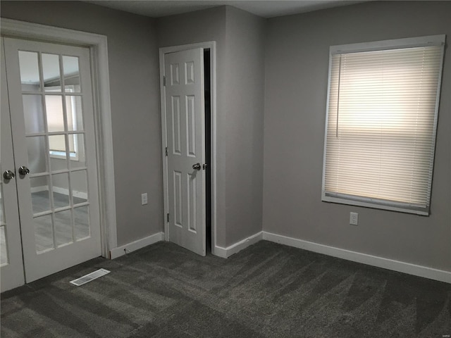 unfurnished room with french doors and dark colored carpet