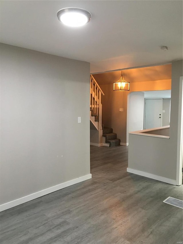 empty room featuring dark wood-type flooring and an inviting chandelier