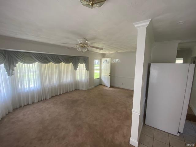 empty room with a wealth of natural light, tile patterned flooring, and ceiling fan