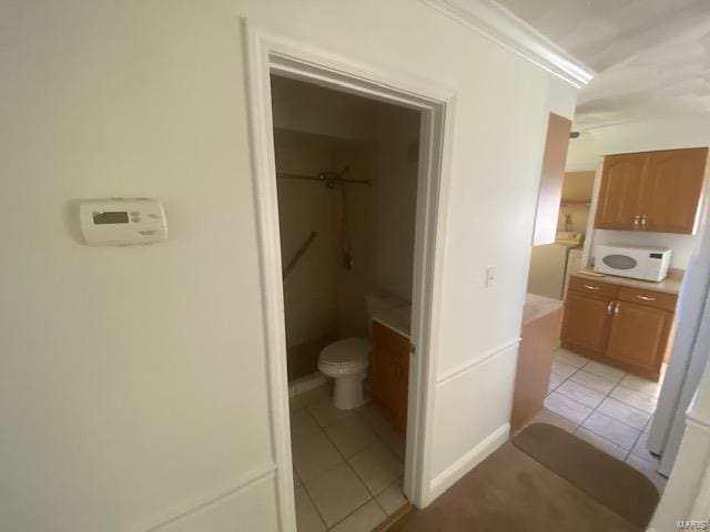 bathroom with tile patterned floors, vanity, toilet, and ornamental molding