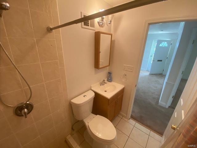 bathroom with tile patterned floors, vanity, toilet, and tiled shower