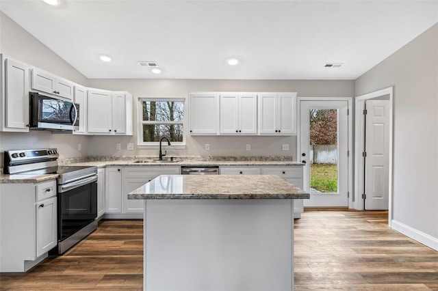 kitchen with appliances with stainless steel finishes, a center island, white cabinetry, and sink