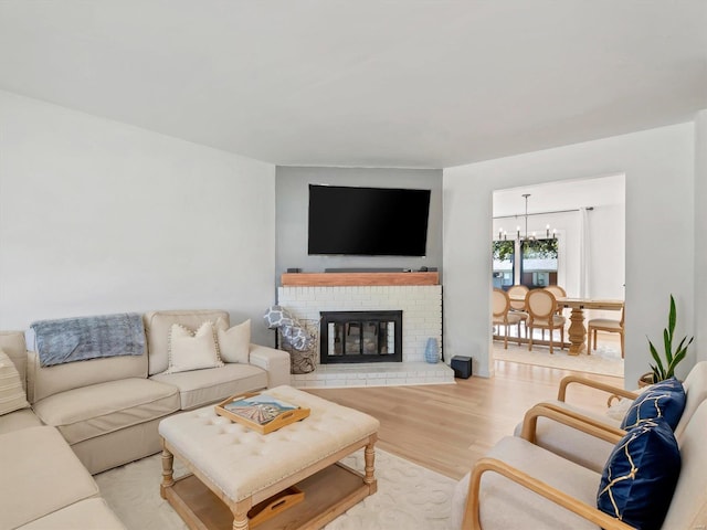 living room with light wood-type flooring, a fireplace, and an inviting chandelier