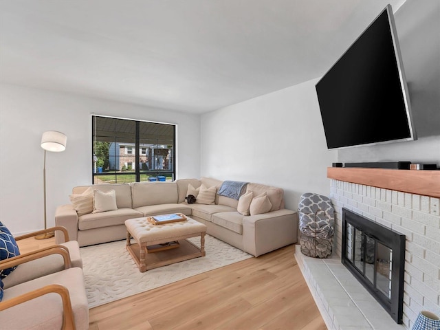 living room featuring light hardwood / wood-style flooring and a brick fireplace