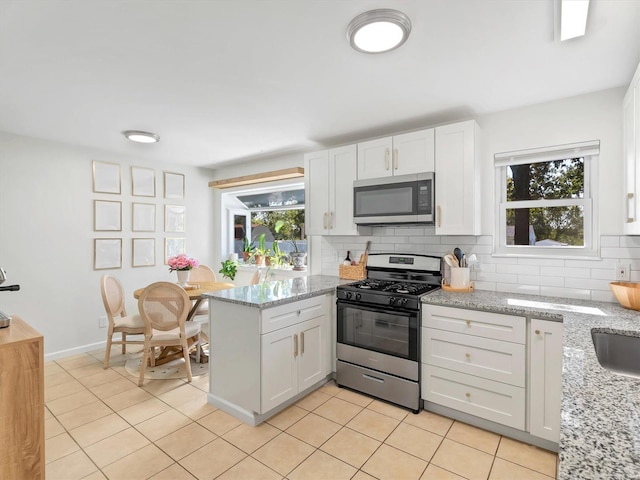 kitchen featuring light stone countertops, white cabinetry, stainless steel appliances, and tasteful backsplash