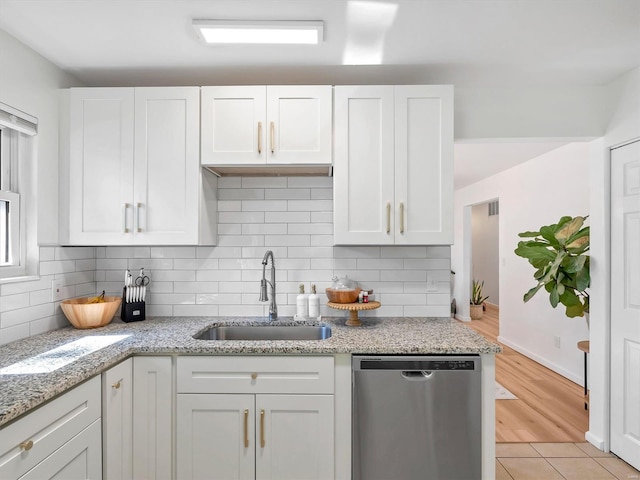 kitchen featuring dishwasher, white cabinets, light stone countertops, and sink