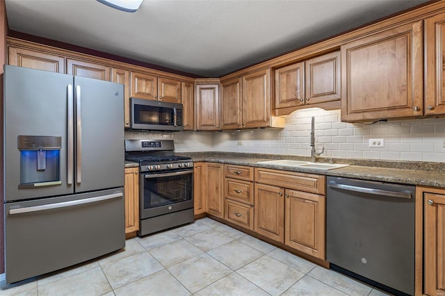 kitchen featuring tasteful backsplash, sink, light tile patterned floors, and stainless steel appliances