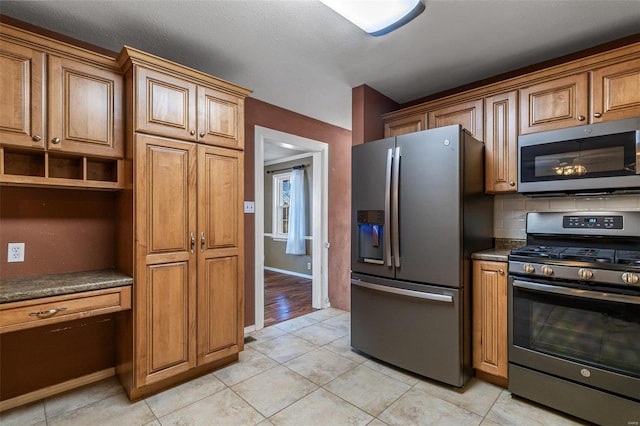 kitchen with tasteful backsplash, light tile patterned floors, and appliances with stainless steel finishes