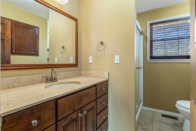 bathroom featuring vanity, tile patterned flooring, a shower with door, and toilet