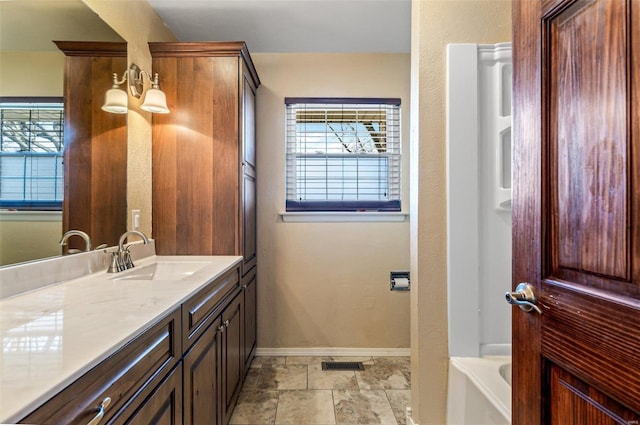 bathroom with a healthy amount of sunlight, a bathing tub, and vanity