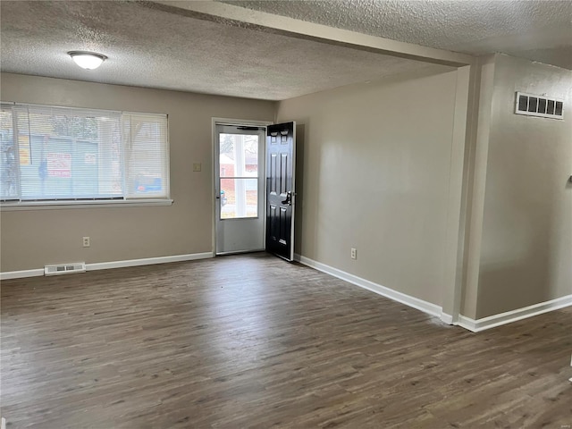 empty room with dark wood-type flooring and a textured ceiling