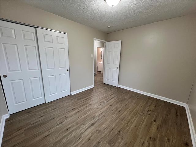 unfurnished bedroom with dark hardwood / wood-style floors, a textured ceiling, and a closet