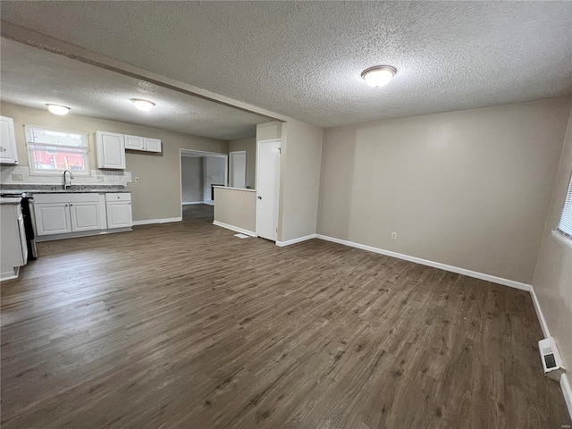 unfurnished living room with dark hardwood / wood-style floors, sink, and a textured ceiling