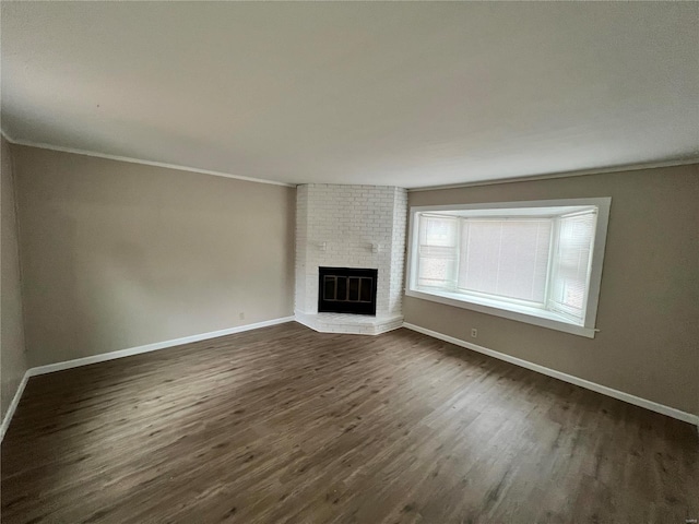 unfurnished living room featuring ornamental molding, dark hardwood / wood-style floors, and a fireplace