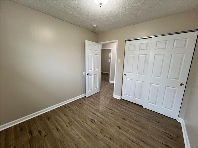 unfurnished bedroom featuring a textured ceiling, dark hardwood / wood-style flooring, and a closet