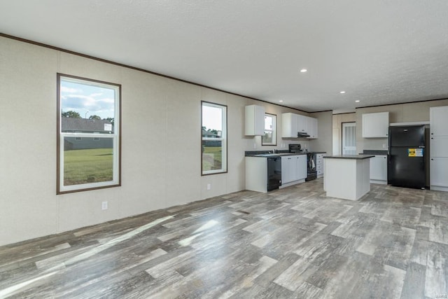 kitchen with ornamental molding, black appliances, a center island, light hardwood / wood-style floors, and white cabinetry