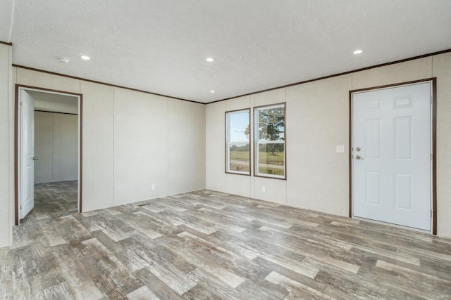 interior space featuring light wood-type flooring, a textured ceiling, and crown molding