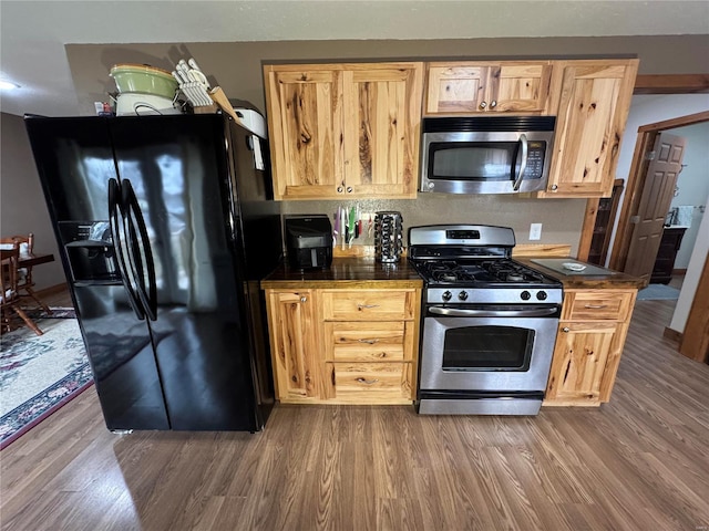 kitchen featuring hardwood / wood-style floors, light brown cabinets, and appliances with stainless steel finishes