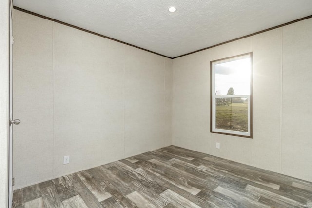 empty room with dark wood-type flooring, a textured ceiling, and ornamental molding