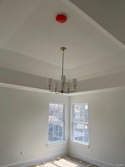 unfurnished room with baseboards and an inviting chandelier