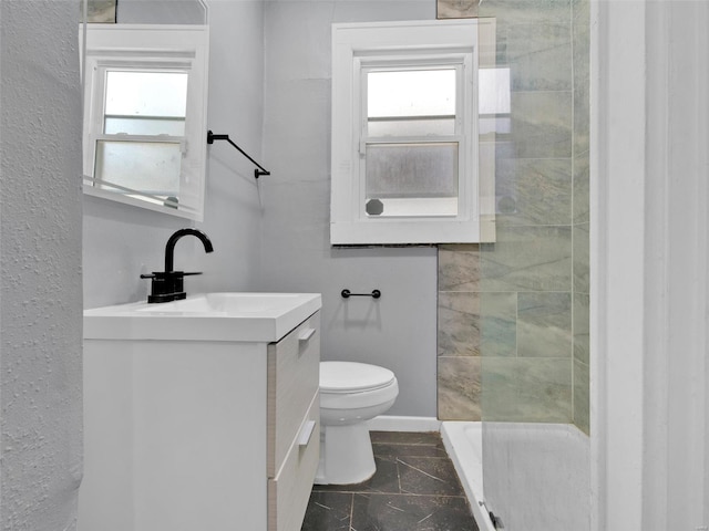 bathroom with toilet, a tile shower, and vanity