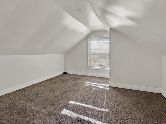 additional living space featuring vaulted ceiling and dark carpet