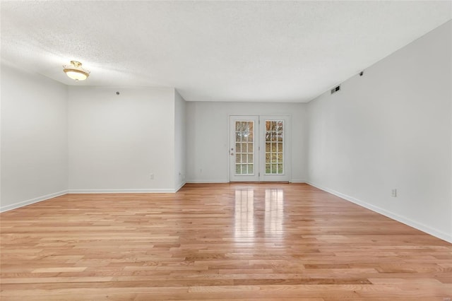 unfurnished room featuring a textured ceiling and light hardwood / wood-style floors