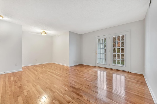 unfurnished room featuring a textured ceiling and light wood-type flooring