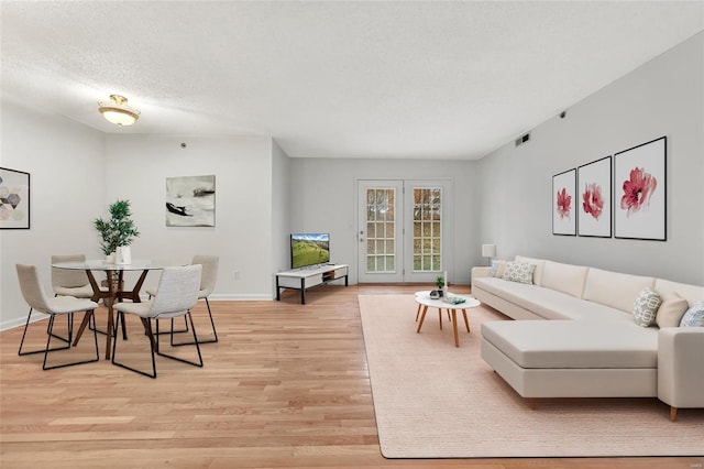 living room with a textured ceiling and light wood-type flooring