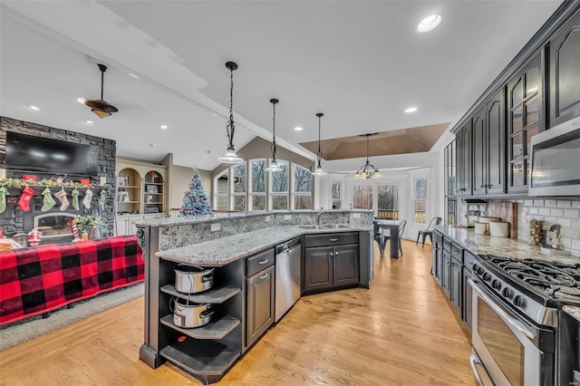 kitchen featuring light wood finished floors, appliances with stainless steel finishes, vaulted ceiling with beams, open shelves, and a sink