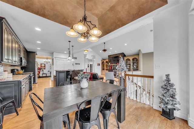 dining space featuring lofted ceiling, light wood-style floors, a notable chandelier, and recessed lighting