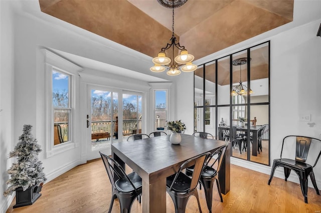 dining space with lofted ceiling, light wood-style flooring, a chandelier, and baseboards