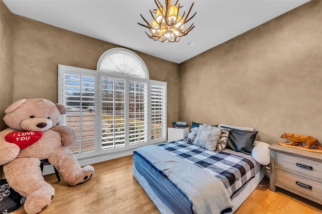 bedroom featuring a chandelier, multiple windows, and wood finished floors