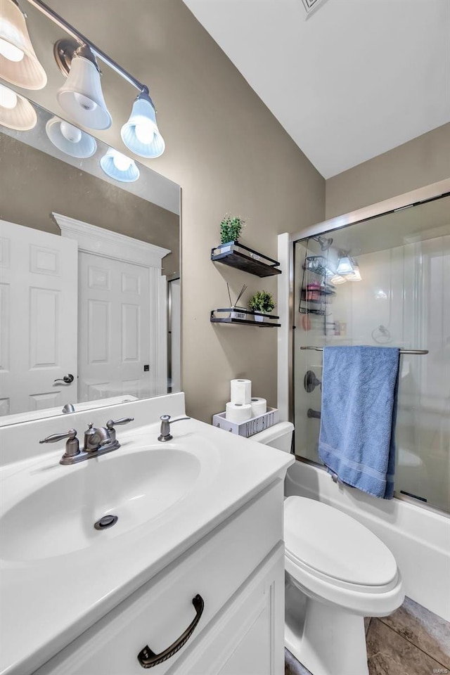 bathroom featuring toilet, shower / bath combination with glass door, and vanity