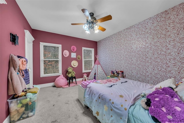 carpeted bedroom with an accent wall, a ceiling fan, baseboards, and wallpapered walls