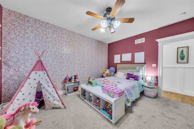 bedroom with a ceiling fan, carpet flooring, visible vents, and wallpapered walls