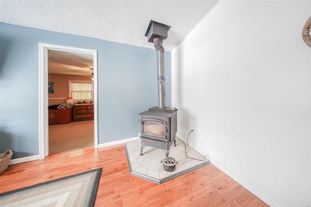 interior details featuring a textured ceiling, wood-type flooring, and a wood stove