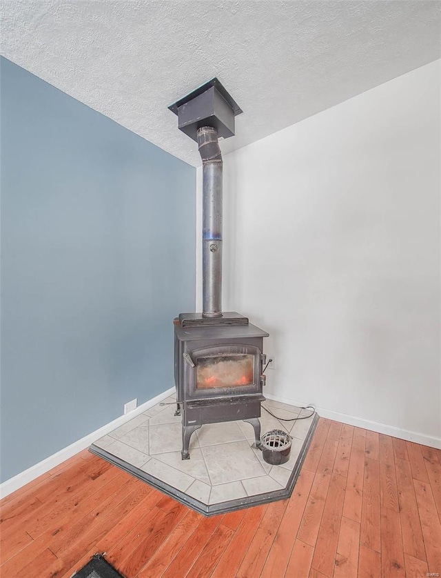 details featuring a textured ceiling, a wood stove, and hardwood / wood-style floors