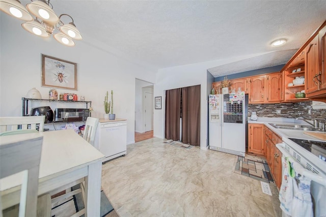 kitchen featuring sink, a textured ceiling, an inviting chandelier, white appliances, and tasteful backsplash