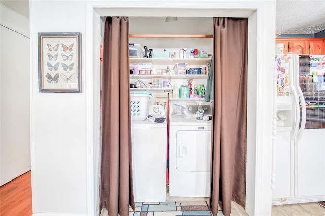 laundry area featuring washing machine and clothes dryer and light hardwood / wood-style floors