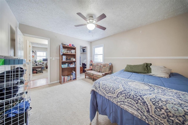 bedroom featuring ceiling fan, multiple windows, carpet floors, and a textured ceiling