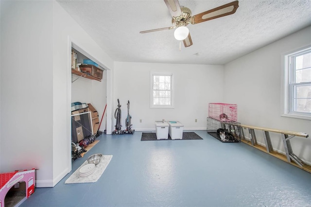 interior space with a textured ceiling, ceiling fan, and concrete flooring