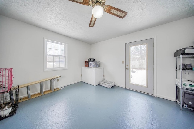 misc room with a textured ceiling, ceiling fan, and a wealth of natural light