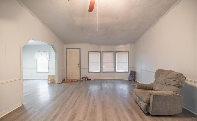 living area with hardwood / wood-style flooring, ornamental molding, and a textured ceiling