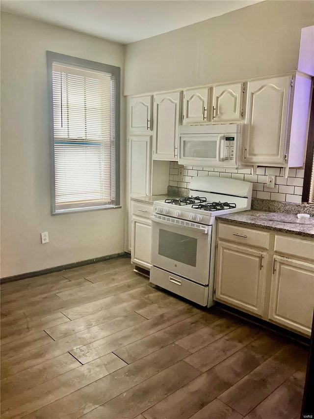 kitchen with decorative backsplash, hardwood / wood-style floors, white cabinets, and white appliances