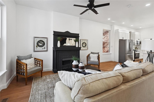 living room featuring ceiling fan and light hardwood / wood-style floors