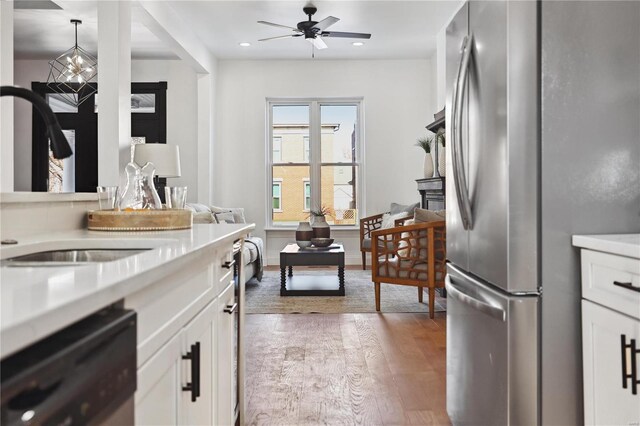 kitchen featuring pendant lighting, ceiling fan, white cabinetry, hardwood / wood-style floors, and stainless steel appliances